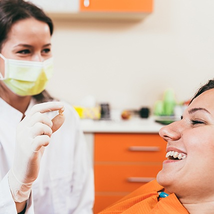 A dentist holding a smiling dental patient’s extracted tooth 