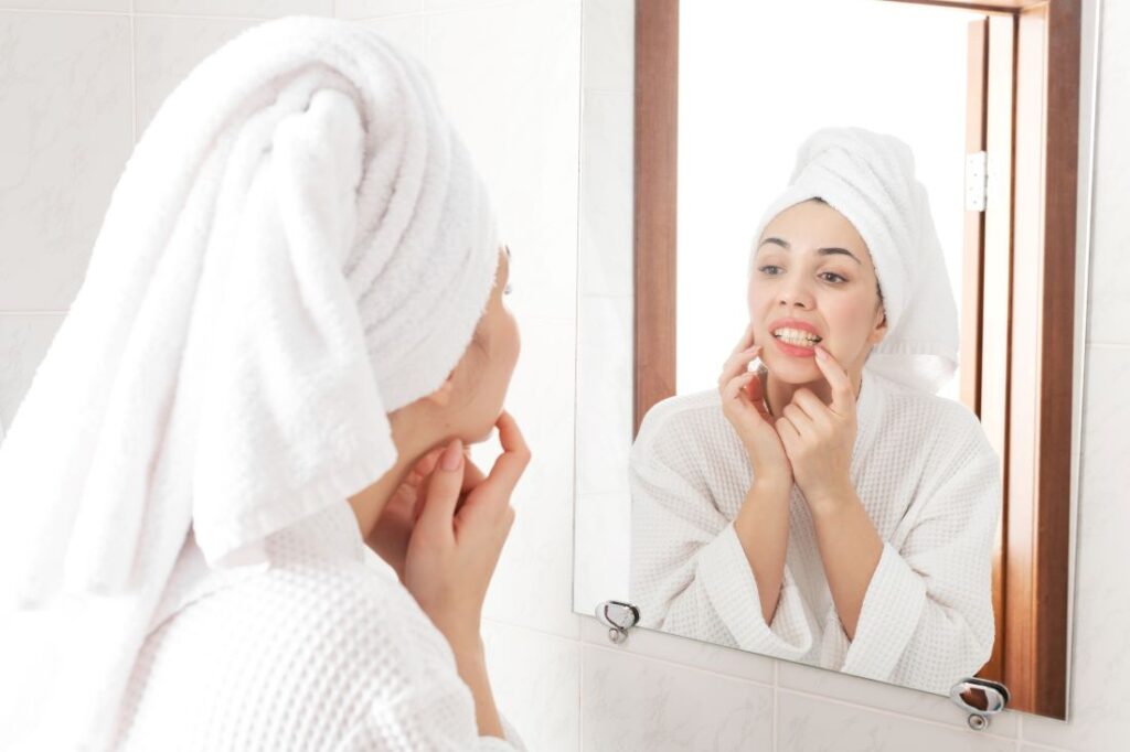 A woman looking at her teeth in the mirror.